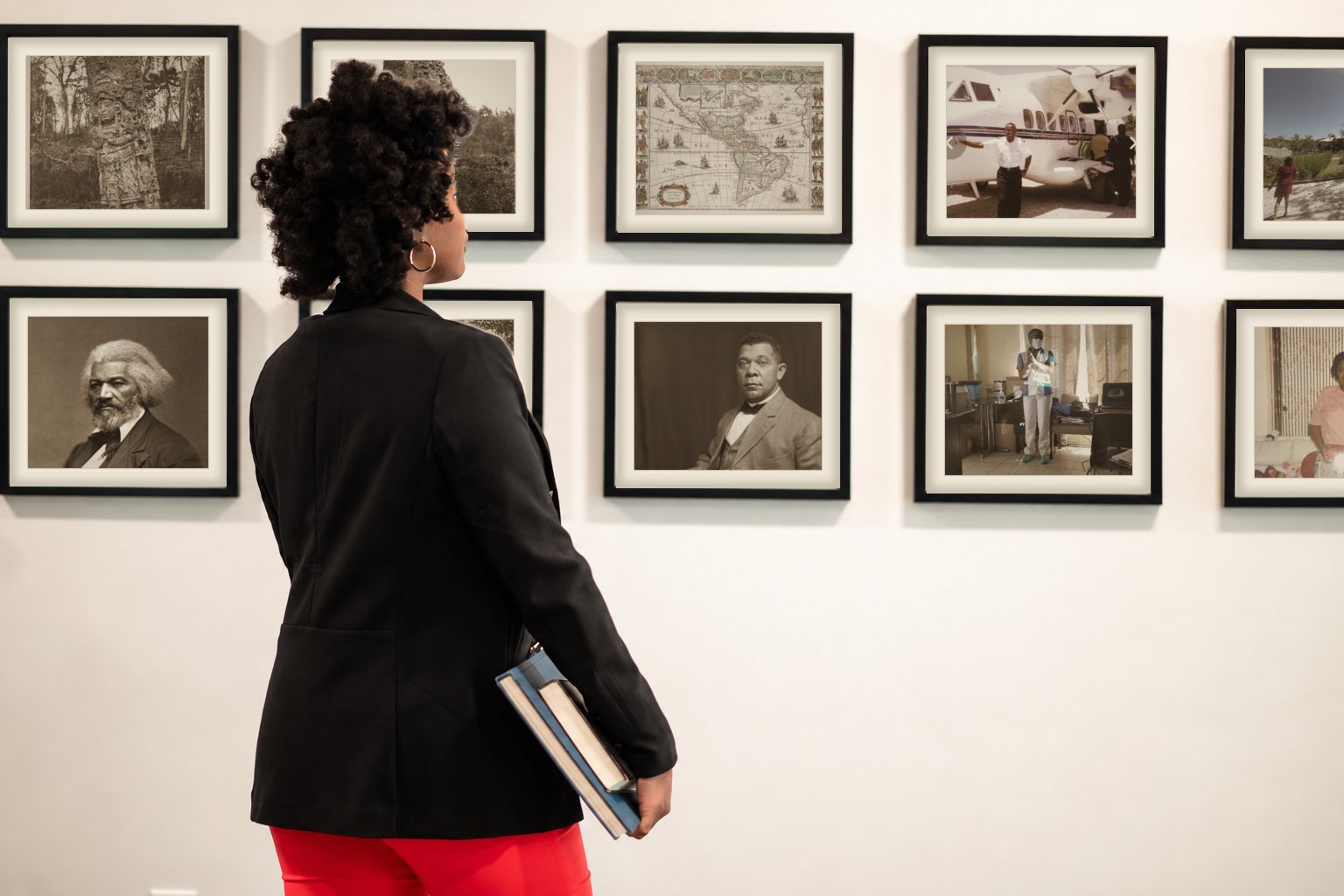 Chief Nnakina Xi-Amaru Fears viewing an archive wall of heritage photographs and a 1665 map of the Americas
